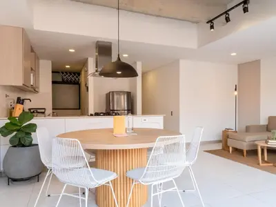 a kitchen with a wooden table and white chairs at NOK Fancy 3BR Balcony in Laureles Medellin in Medellín