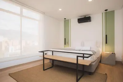 a bedroom with a bed with a bench and a window at NOK Amazing with Balcony 3 BR in Laureles Medellin in Medellín