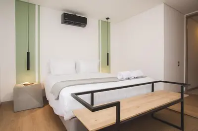 a bedroom with a large bed and a bench at NOK Perfect 3 BR in Laureles in Medellin in Medellín