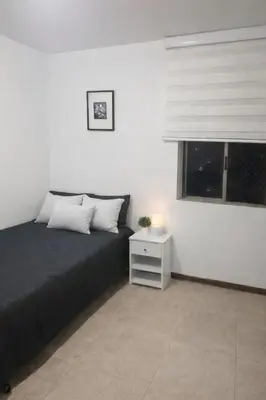 a bedroom with a bed with a night stand and a window at Apartment near Atanasio Girardot Stadium in Medellín