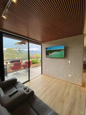 a living room with a couch and a television on a wall at San Telmo Guatape Apto con Jacuzzy in Guatapé