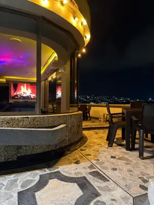 a patio with tables and chairs on a roof at night at Lu alojamiento parque caldas in Manizales