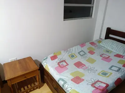 a bed with a quilt on it next to a table at Ninfa del Mar Hostal Turístico in Manizales