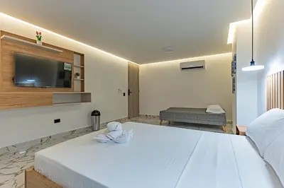 a bedroom with a large white bed with a flat screen tv at loft 72 holiday inn medellin in Medellín