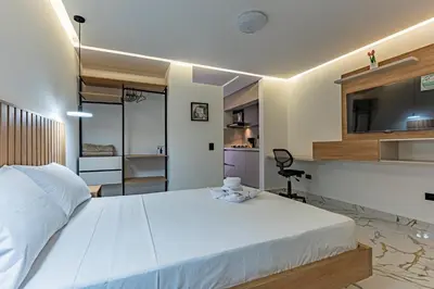 a bedroom with a large white bed and a kitchen at Apartaloft exclusivo en laureles in Medellín