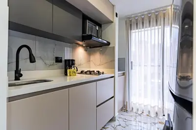 a kitchen with white cabinets and a sink and a window at Exclusivo Urban Loft en Laureles in Medellín