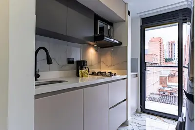 a kitchen with white cabinets and a sink and a window at Exclusivo Urban Loft en Laureles in Medellín