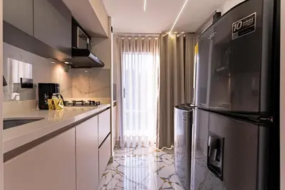 a kitchen with white cabinets and a stainless steel refrigerator at Apartaloft exclusivo en laureles in Medellín
