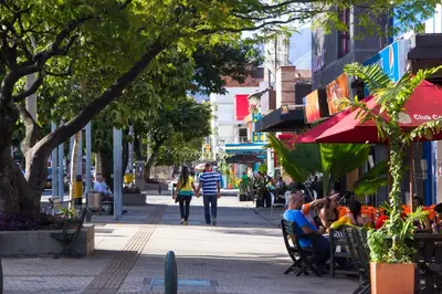 a group of people sitting in chairs on a city street at Apartasuites AV in Medellín