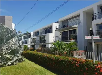 a large white apartment building with bushes and trees at Apartasol Santafe de Antioquia in Santa Fe de Antioquia