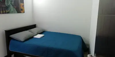 a small bedroom with a bed with a blue blanket at Apartasol in Santa Fe de Antioquia