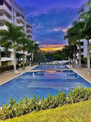 a large swimming pool with palm trees in front of a building at Hermoso Apartasol San Jeronimo in San Jerónimo