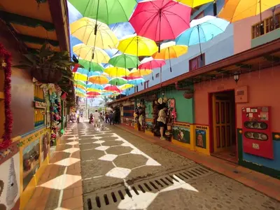 a street with colorful umbrellas hanging from the ceilings at Aptos y Apartaestudios frente al Malecón y el Embalse, Zona Gastronómica, a 8 minutos de la Piedra del Peñol, TODO CERCA!!! in Guatapé