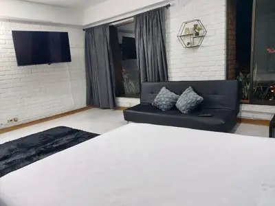 a bedroom with a bed and a black couch at Loft Poblado Park in Medellín