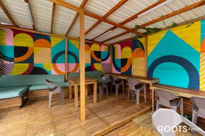 a room with tables and chairs and a colorful wall at Hospedaje cerca a centro comercial de Santafé A104 By Roots Rentals in Medellín