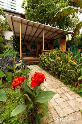 a garden with red flowers in front of a building at Hospedaje cerca a centro comercial de Santafé A104 By Roots Rentals in Medellín