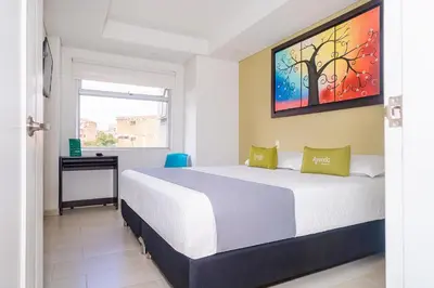 a bedroom with a bed and a desk and a window at HOTEL OASIS in Rionegro